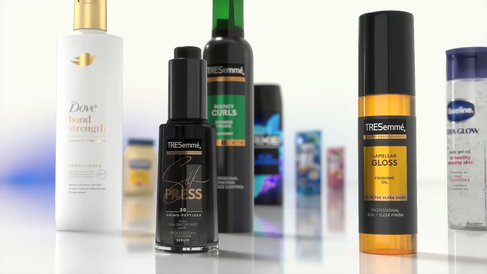 Nærbilde av diverse hår- og kroppspleieprodukter utstilt på en reflekterende overflate. Synlige gjenstander inkluderer Dove Bond Strength balsam, TRESemmé Silk Press serum, TRESemmé Lamellar Gloss finishing oil og andre Unilever-produkter i bakgrunnen.